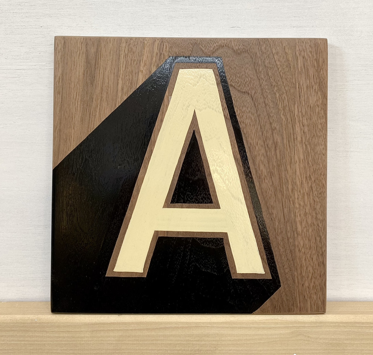 Stylish lettering! This is a bespoke, hand-painted letter A in cream and black on a hardwood surface.